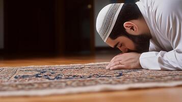 Man in prayer with hands clasped on a prayer rug indoors photo