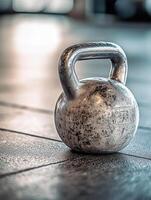 Close-up of a kettlebell on a gym floor with textured handle and smooth surface in bright natural light photo