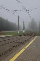 Railway, tramway, rails go into fog. Axial landscape photo