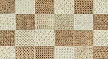 A brown and white rug with squares of crochet photo