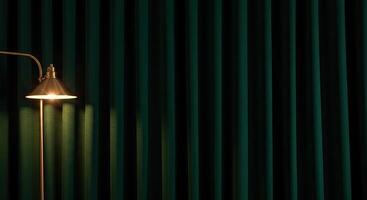 A lamp is sitting on a table next to a green curtain photo