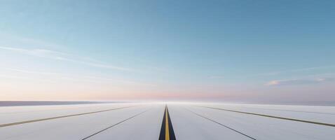 An empty runway with a blue sky and a yellow line photo