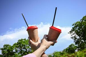 Two cups of paper coffee, relaxing in a sunny spring green urban park in nature. The concept of urban leisure. photo
