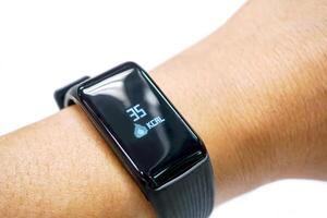 Closeup human's hand wear black healthy smart band with numbers and icon of calories burned display on screen isolate on white background. photo