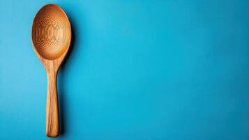 Elegant Minimalist Wooden Spoon Situated Against a Solid Blue Background Perfect for Kitchen and Culinary Themed Designs photo