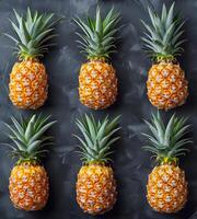 Pineapples on a black grunge background are arranged in a row photo