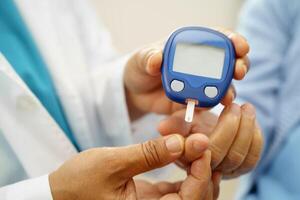 Asian doctor using digital glucoeter for check sample blood sugar level to photo