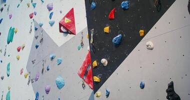 A man is climbing wall with many different colored rocks video