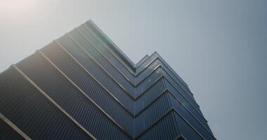 Bottom view of a modern glass skyscraper against a clear sky video