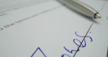 A pen is resting on a document with a signature video