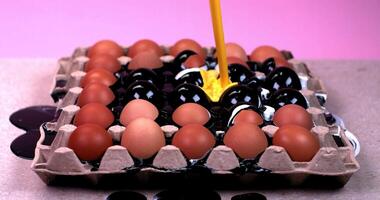 Yellow, black and white paint is poured into an eggs tray video