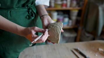 Potter hands with cutter make holes on cup for coupling and connection with handle in art workshop video