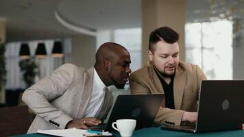 Two multiracial colleagues engaging in a discussion during a business meeting in a conference room. Happy business people, men, collaborating and working towards their shared goals video