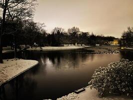 Winter evening landscape of a snowy park with a calm reflective lake photo