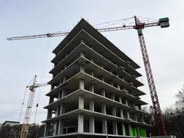 Modern construction site with building framework and cranes under cloudy sky photo