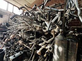 A heap of metal exhaust pipes and canisters in a rustic workshop setting photo