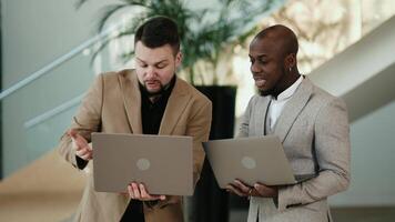 Two business men work and converse in the lobby of a modern business center, preparing for a business meeting or conference. Concept business solutions, productivity, and successful collaboration video