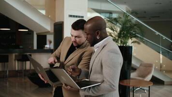 Two business men work and converse in the lobby of a modern business center, preparing for a business meeting or conference video