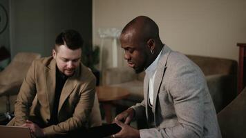Two professional colleagues, a man and a woman, are engaged in a discussion while reviewing information on laptop computer. They demonstrate teamwork, collaboration, and a tech-savvy workplace video