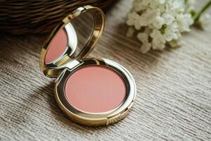 A small pink compact powder sits on a table next to a white flower photo