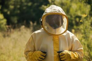 A person in a yellow and white beekeeper suit is wearing a face mask photo