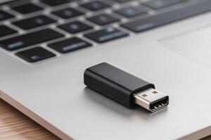 A black USB drive sits on a laptop keyboard photo