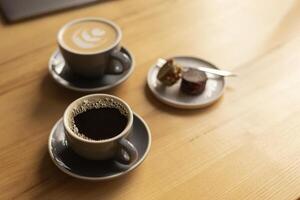 two cups of coffee and a plate with sweets on a table in a cafe photo