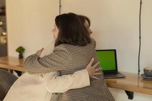 successful project, two women were working at computers and joyfully hugging photo
