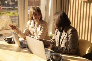two women are discussing at computers in a co-working space photo