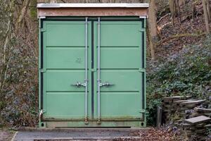 Green shipping container storage unit in a forest setting photo