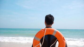 Man in a rescue uniform, standing near the shoreline with the sea behind him. For blogs on emergency preparedness, public safety, working as a lifeguard photo