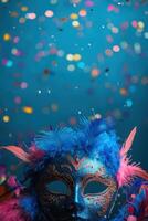 A blue carnival mask with feathers and colorful confetti photo