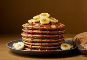 A Stack of Buttery Pancakes Topped with Banana Slices and Syrup photo