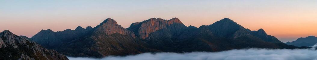 Jagged mountain peaks rise into the dawn sky photo