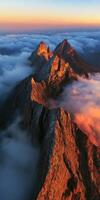 Majestic jagged mountains rise above clouds at sunset photo