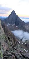 Jagged mountain peak rising above clouds at dusk photo