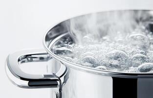 Boiling water in a stainless steel pot on a clean surface photo