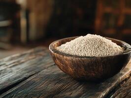 Grey flour sits in a wooden bowl on a rustic table photo