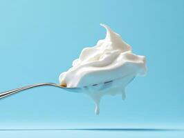 Creamy whipped topping on a spoon against blue background photo