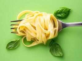 Pasta served on a fork with fresh basil on green background photo
