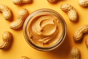 Peanut butter jar surrounded by peanuts on a yellow background photo