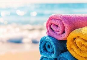 Colorful rolled towels beside shimmering ocean waves at the beach photo