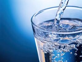 Refreshing clear water pours into a glass filled with bubbles photo