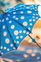Blue polka dot beach umbrella stands on sandy shore under warm sunlight during summer afternoon photo