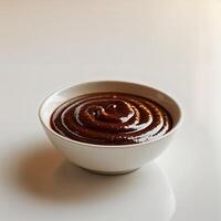 Thick chocolate sauce swirled in a white bowl on a smooth surface with soft lighting photo