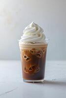Refreshing iced coffee topped with whipped cream served in a clear cup on a light background photo