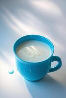 Blue cup filled with fresh milk resting on a white surface in sunlight photo