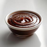Rich chocolate sauce presented in a small white bowl on a clean surface photo