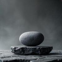 Smooth dark stone balanced on a rough stone slab in soft natural light photo