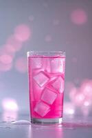 Refreshing pink beverage with ice cubes in a tall glass set against a soft, bokeh background photo